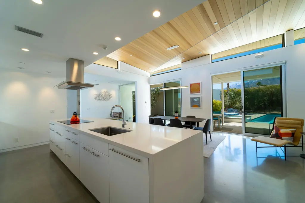 Cocina blanca con techo de madera y vistas al jardín