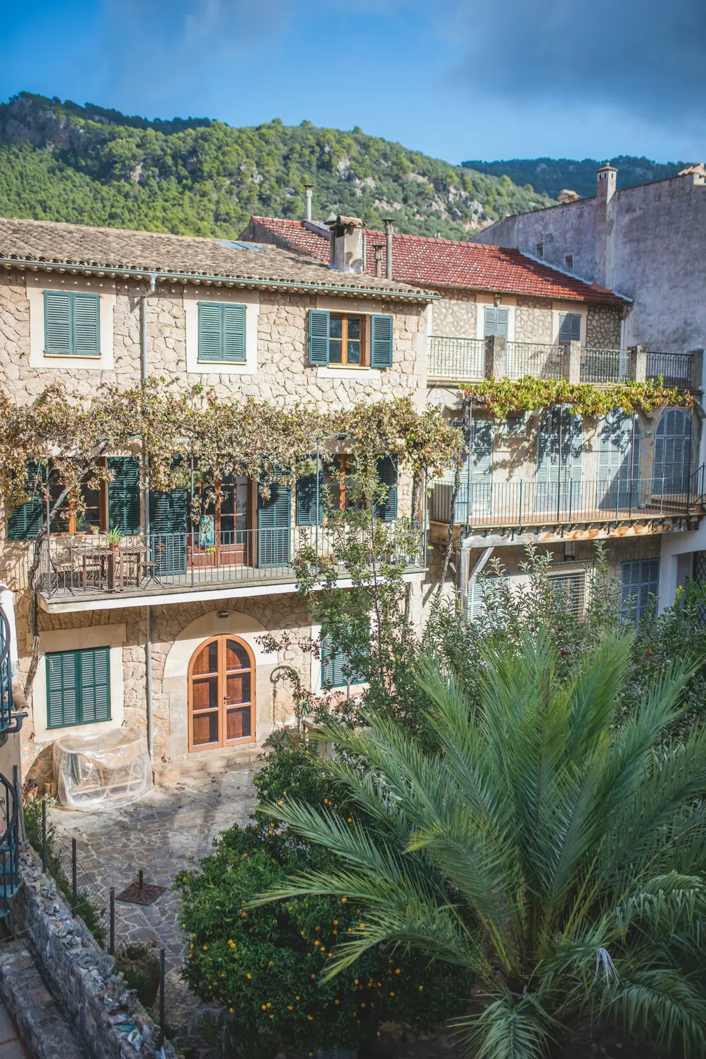 Fachada de piedra con parra, balcones y puerta en arco